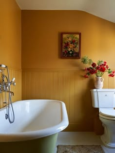 a white bath tub sitting next to a toilet under a painting on the bathroom wall