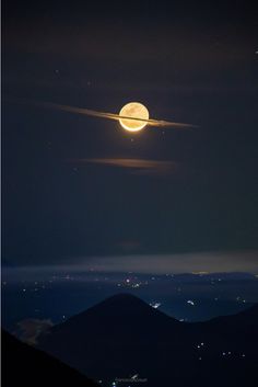 the moon is shining brightly in the night sky above some hills and mountains with clouds