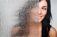 a woman with long black hair and brown eyes is smiling at the camera while she has rain on her face