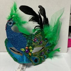 a blue mask with green feathers on it