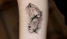 a lion and cub tattoo on the left inner arm, which is black and white