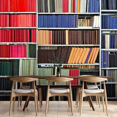 three wooden chairs sitting in front of a book shelf filled with books