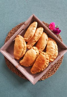 a basket filled with pastries sitting on top of a blue cloth covered floor next to a pink flower