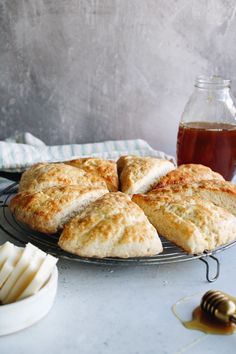 biscuits and honey sit on a table next to a jar of honey