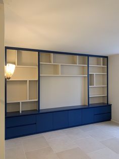 an empty room with blue and white bookcases on the wall next to a lamp