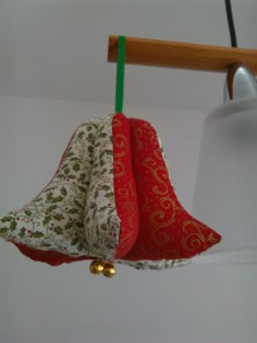 two red and white bells hanging from a wooden hook in a room next to a lamp