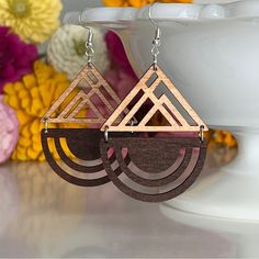 wooden earrings with geometric shapes on them and flowers in the backgroung background