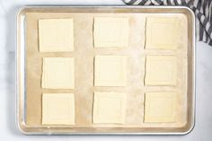 a pan filled with squares of butter on top of a white counter next to a black and white towel