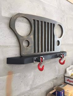 there is a metal grill on the wall with two hooks attached to it and some boxes underneath