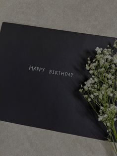 a bouquet of white flowers sitting on top of a black card that says happy birthday