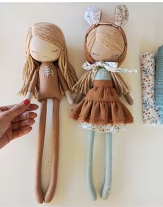 two dolls are sitting next to each other with hair clips in front of them, and one doll is wearing a brown dress