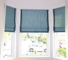 two windows with blue roman shades in a white room