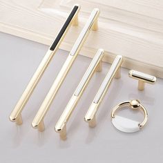 four different types of metal door handles on a white surface next to a pair of rings