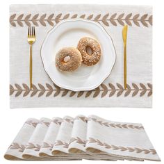 a white plate topped with two donuts next to fork and napkins on top of a table