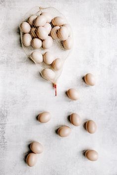 several eggs in a mesh bag on a white surface with one egg being dropped from the net