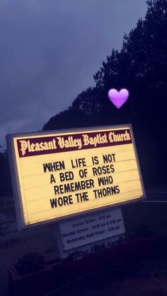 a sign that is in front of a church with a pink heart on it's side