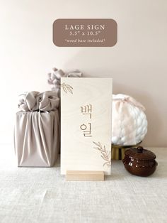 a wooden sign sitting on top of a table next to two vases with flowers