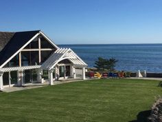 a large house sitting on top of a lush green field next to the ocean