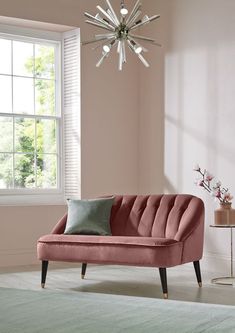 a pink couch sitting in front of a window