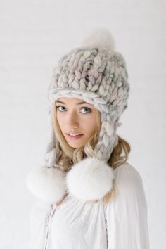 a woman wearing a knitted hat and scarf with pom - poms on it