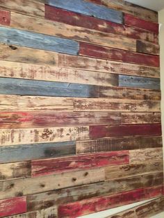 a bathroom wall made out of wood planks and painted with red, blue, yellow and white paint