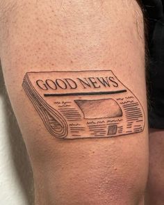 a man's leg with a newspaper tattoo on it that reads good news and has an image of a rolled up newspaper