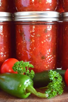 tomatoes, peppers and other vegetables sit in front of jars filled with canned rote - style tomato sauce