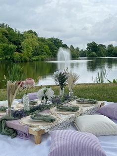 a picnic table with flowers and greenery on it near the water's edge