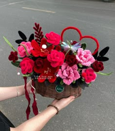 a person holding a basket with flowers in it on the side of the road,