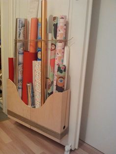 a wooden shelf filled with lots of wrapping paper and other crafting supplies on top of a hard wood floor