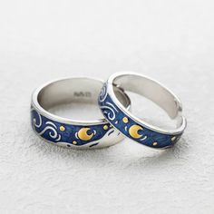 two wedding rings with blue and yellow designs on them sitting next to each other in front of a white background