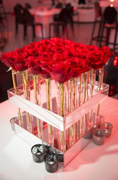 a clear box with red roses in it on top of a table at a wedding