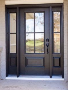 a black front door with two sidelights and glass panels on the top half of it