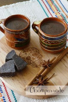 two mugs of hot chocolate on a cutting board with cinnamon sticks and star anise