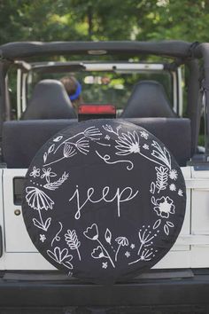 a black and white tire cover that says keep on the back of a jeep with flowers painted on it