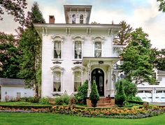 a large white house sitting on top of a lush green field