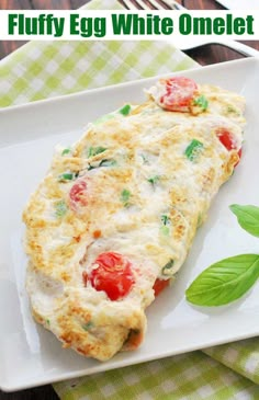 an egg omelet with tomatoes and spinach on a white plate next to a fork