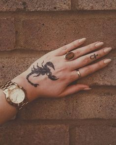 a woman's hand with a scorpion tattoo on it and a watch around her wrist