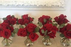 five vases with red roses in them on a table