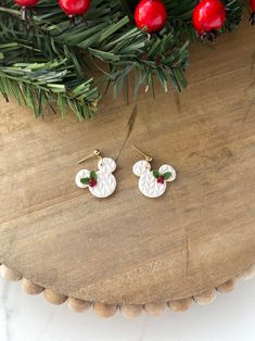 the earrings are decorated with holly leaves and white snowflakes on top of a wooden table