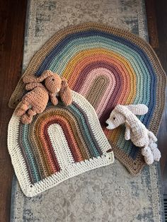 a crocheted rug with two stuffed animals on it and a rainbow shaped blanket