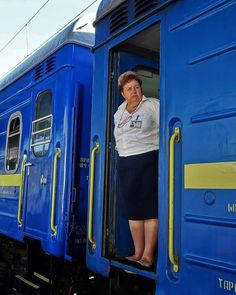 a woman standing in the doorway of a blue train