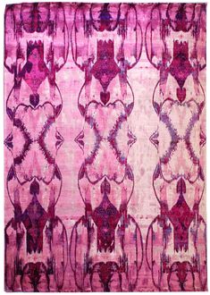 a pink rug with an intricate design on the front and back side, in shades of purple