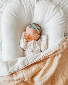 a baby laying on top of a white pillow