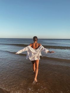 a woman is walking in the water at the beach