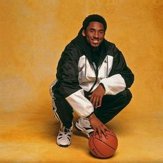 a man kneeling down with a basketball in his hand and smiling at the camera while posing for a photo