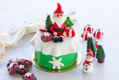 a cake decorated with santa clause sitting on top of it next to other christmas decorations