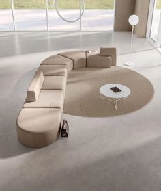 a modern living room with an oval couch and round coffee table in the middle, surrounded by large windows