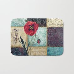 a bath mat with a red flower on top of it and writing underneath the image