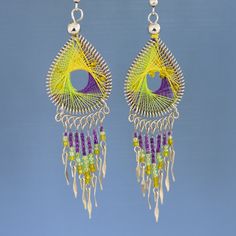 a pair of yellow and purple beaded earrings on a blue background with white beads